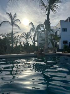 una donna sdraiata in una piscina con palme di Villas Del Scarlet Cardones a Pescadero