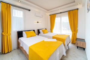 2 łóżka w pokoju z żółtymi zasłonami w obiekcie Villa Ruya by Sakina Escapes w mieście Fethiye