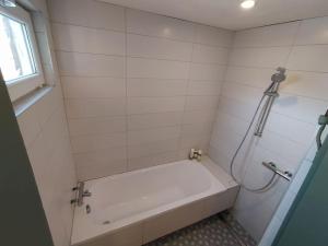 a white bathroom with a tub and a shower at Hillside country house - Long stays in Vilnius