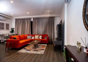 a living room with a red couch and a table at Manjaro Luxury Suites at Stella Place, East Legon in Accra