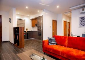 阿克拉的住宿－Manjaro Luxury Suites at Stella Place, East Legon，一间带红色沙发的客厅和一间厨房