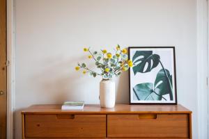 a vase of flowers on a dresser with a picture at Cosy Harrogate Haven in Harrogate