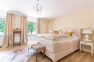 a white bedroom with a large bed and a chandelier at Waldhotel und Restaurant Zeitreise in Bramsche
