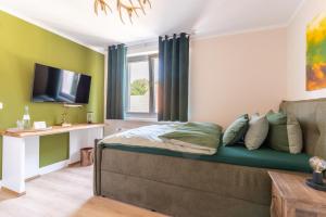 a bedroom with green walls and a bed with a couch at Waldhotel und Restaurant Zeitreise in Bramsche