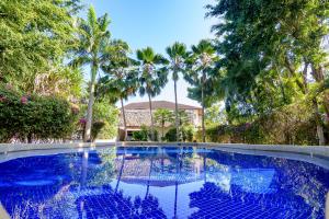 una piscina azul con palmeras en el fondo en Minimi Couzy villa casaurina en Malindi