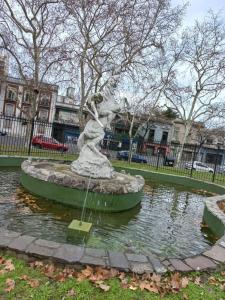 una estatua de una mujer en un estanque en un parque en Vista verde encantadora en Buenos Aires
