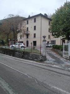 a white building with a fence next to a street at Casa Mirtillo in Lizzano in Belvedere