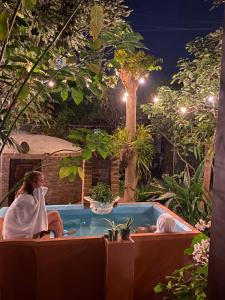 a woman sitting in a hot tub in a garden at night at RUAJ HOSTAL -Wellness-Colonial-Exclusive- in Antigua Guatemala