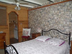 a bedroom with a bed and a stone wall at Chez Jean Marc et Corinne in Priay