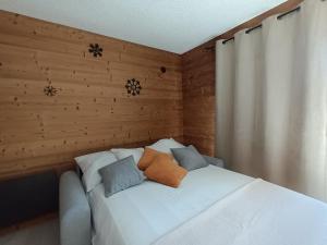 een wit bed in een kamer met een houten muur bij Appartement montagne LE FLOCON in Saint-Michel-de-Chaillol