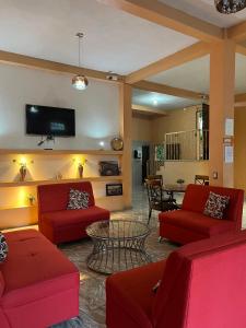 un soggiorno con divani rossi e TV di Hotel y Restaurante La Perla, Cacaopera, Morazan, El Salvador a Cacaopera