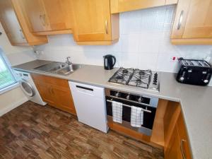 a small kitchen with a stove and a sink at No 23- Large Spacious 3 Bed Home - Parking & WiFi in Nantwich