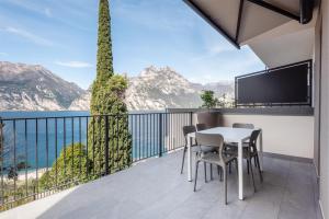 einen Balkon mit einem Tisch und Stühlen mit Blick auf das Wasser in der Unterkunft Apartment Bellavista in Nago-Torbole