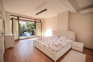 a bedroom with a white bed and a large window at Green Oasis in the City Center in Pristina
