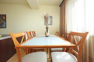AM Apartments 1 في يريفان: طاولة طعام مع كراسي و مزهرية مع الزهور