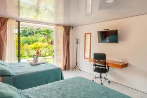 a bedroom with two beds and a desk and a window at Hotel Secreto La Fortuna in Fortuna