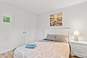 a white bedroom with a bed and a nightstand at Beachy Getaway - Cozy and Secluded Lodge Home in Knightdale