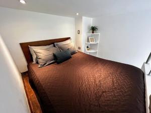 a bedroom with a large brown bed with two pillows at Urban Shelter, El Dorm. in Guatemala