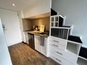 a small kitchen with white cabinets and a microwave at Urban Shelter, El Dorm. in Guatemala