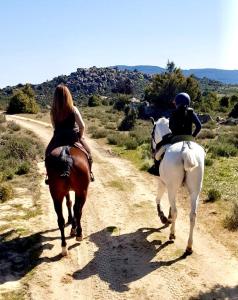 two people riding horses down a dirt road at La Casita El Berrueco in El Berrueco