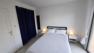 a bedroom with a white bed and two lamps on tables at Sunny Mercury - Room in Apartment in Cannes