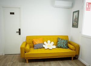 um sofá amarelo com almofadas e uma flor branca em SG ROOMS em Consuegra