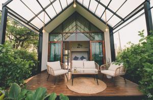 un porche cubierto de una casa con 2 sillas y una mesa en Nana Field Cabin 3, en Ban Phra Fang