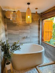 Una bañera en un baño con luces colgantes. en Nana Field Cabin 3, en Ban Phra Fang