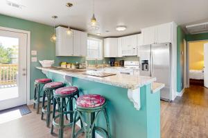 a kitchen with white cabinets and bar stools at Lazy River, Lazy Days in Shoreline Park