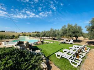 a group of white lounge chairs and a swimming pool at Glamping Turquesa, feel and relax in a wood house in Corredoura