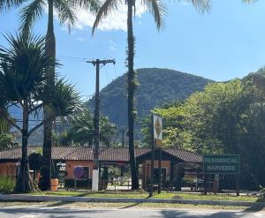a building with palm trees in front of a mountain at Condomínio Mar Verde Caraguatatuba - CASA 55 in Caraguatatuba