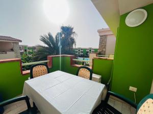 a table and chairs on a balcony with a green wall at Cozy Apartment with Pool, near Beach and Center in Santa Maria