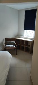 Cette chambre comprend un lit, une chaise et une fenêtre. dans l'établissement Appartement Dumortier, à Knokke-Heist