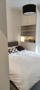 1 dormitorio con cama blanca y lámpara negra en Appartement Dumortier, en Knokke-Heist