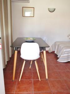 a black table with a white chair and a bed at Apartamentos Salema Praia Club in Salema