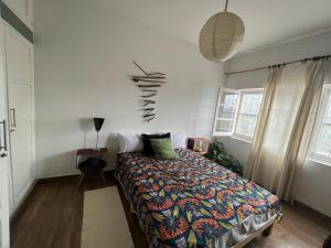 ein Schlafzimmer mit einem Bett mit einer bunten Decke in der Unterkunft Ponta Mina Room in São Tomé