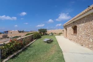 a garden with a bench next to a stone building at Dammuso Ignazio in Lampedusa