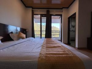 a bedroom with a large bed with a large window at Hotel 7 Heavens in Mussoorie