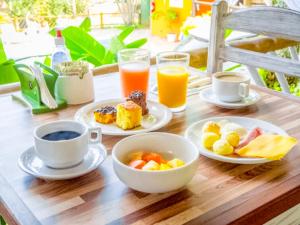 - une table en bois avec des assiettes de produits pour le petit-déjeuner et des boissons dans l'établissement VELINN Pousada Aporan Ilhabela, à Ilhabela