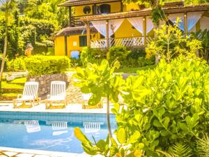 a house with a swimming pool in front of a house at VELINN Pousada Aporan Ilhabela in Ilhabela