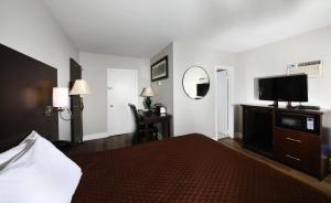 a hotel room with a bed and a flat screen tv at Cedar Lodge Motel in Goderich