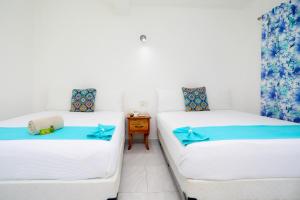 two beds in a room with white walls and blue curtains at Hotel Maria de Lourdes in Cancún