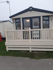 a house with a white porch and a white fence at Swift Burgundy in Prestatyn
