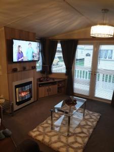 a living room with a fireplace and a tv at Swift Burgundy in Prestatyn
