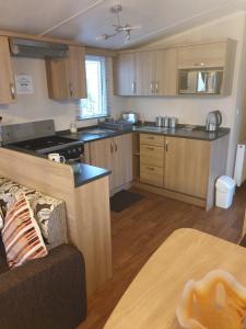 a kitchen with wooden cabinets and a couch in a room at Swift Burgundy in Prestatyn