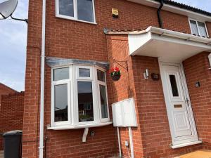 a brick house with a window and a flower pot at CONTRACTORS OR FAMILY HOUSE - M1 Nottingham - IKEA RETAIL PARK - CATKIN DRIVE - 2 Bed Home with Driveway, private garden, sleeps 4 - TV'S in all rooms 
