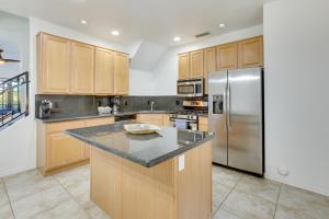 a kitchen with wooden cabinets and a stainless steel refrigerator at Rooftop Patio, Skyline Views Phoenix Townhome! in Phoenix