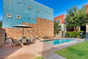 a patio with a table and an umbrella next to a building at Rooftop Patio, Skyline Views Phoenix Townhome! in Phoenix