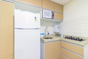 a kitchen with a white refrigerator and a sink at Villa Del Mar #101 - Suíte em Porto por Carpediem in Porto De Galinhas