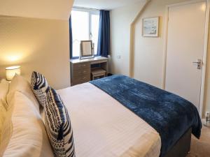 a bedroom with a bed and a desk and a window at Chalfont Lodge in Skegness